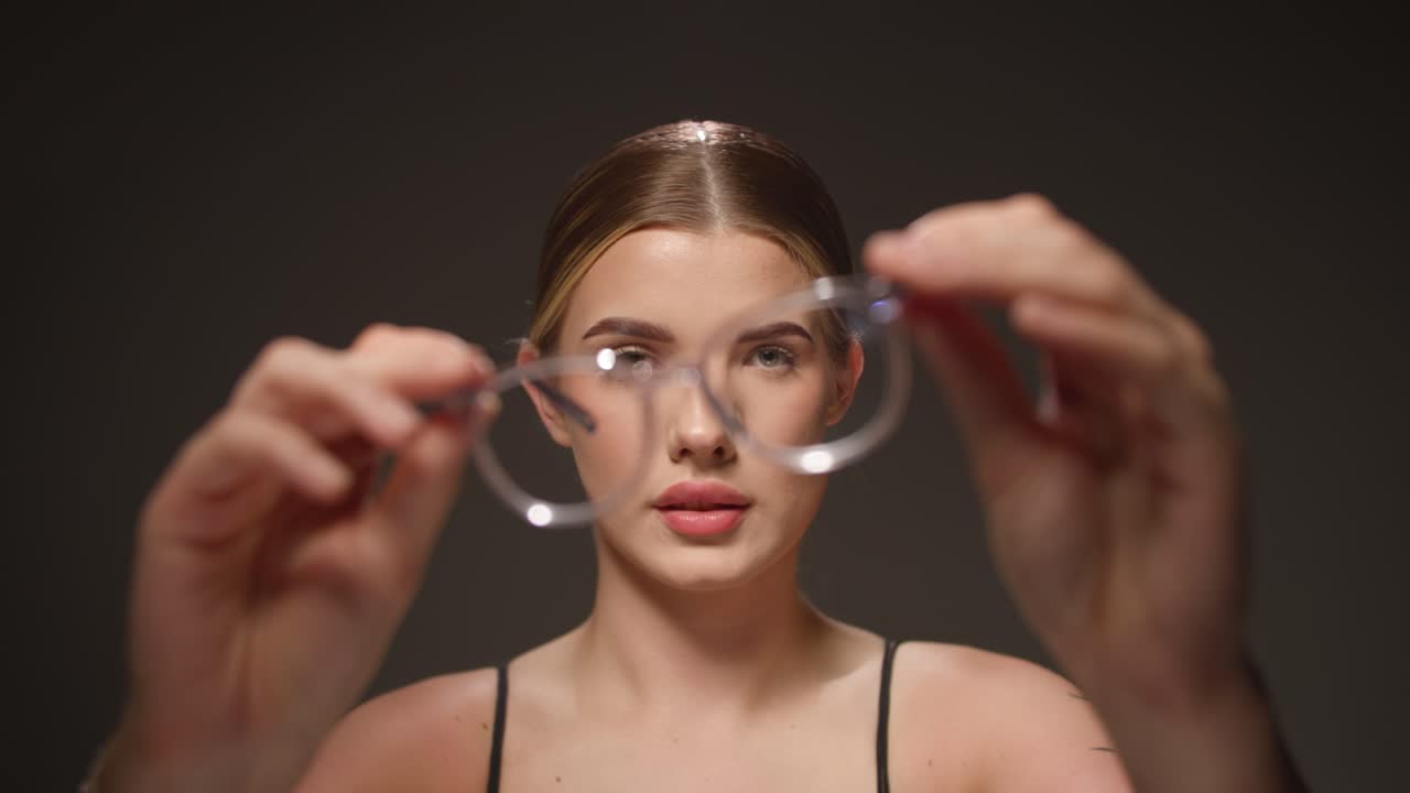joven inteligente mira sus nuevas gafas, sonrisa feliz, estudio