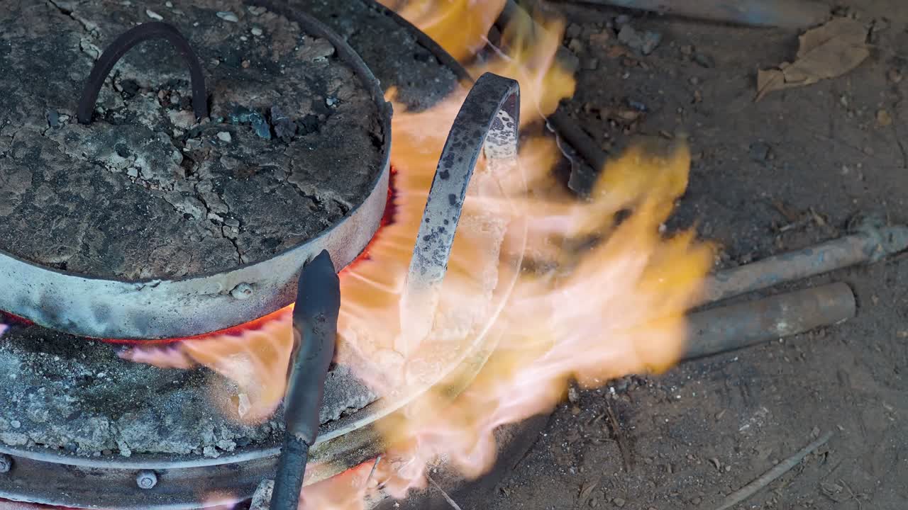 Fire bursts from sealed floor crucible where metal is slowly melted in a traditional bell foundry using an age-old underground heating method before casting, slow motion, Crema, CR, Italy