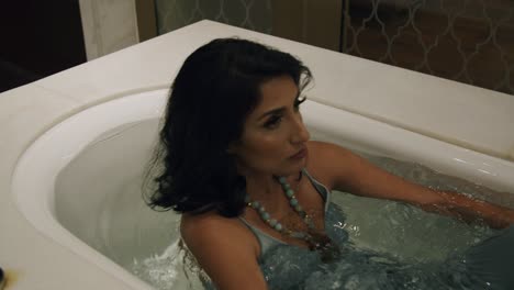 woman in elegant clothes falls back into tub filled with water - static, medium shot