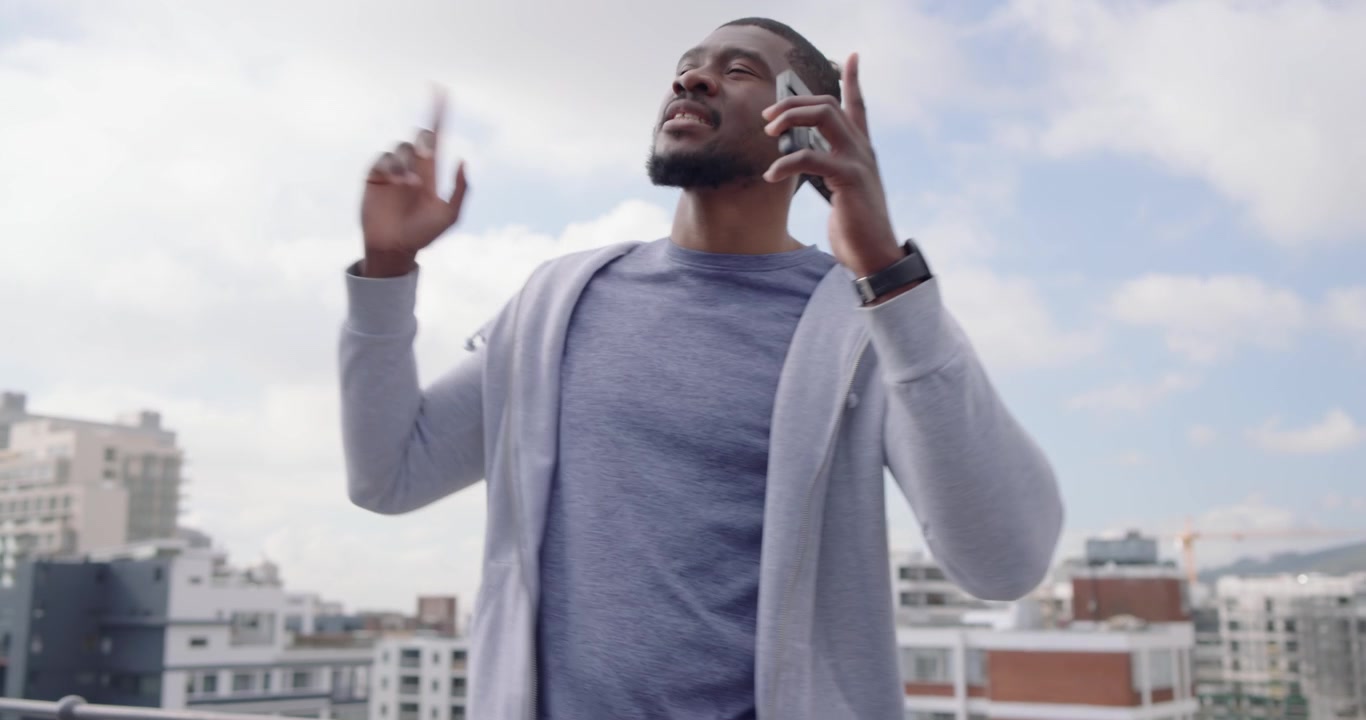 Uomo sui trentacinque anni che tocca il telefono, avvia la musica, ascolta e balla su una terrazza panoramica con le cuffie.