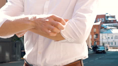 man adjusting sleeves of white dress shirt in city