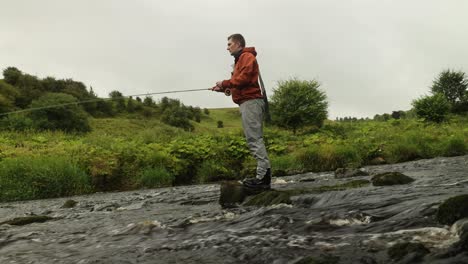 Low-Angle-Aufnahme-Eines-Fliegenfischers,-Der-Seine-Rute-Und-Leine-In-Einen-Fluss-Wirft