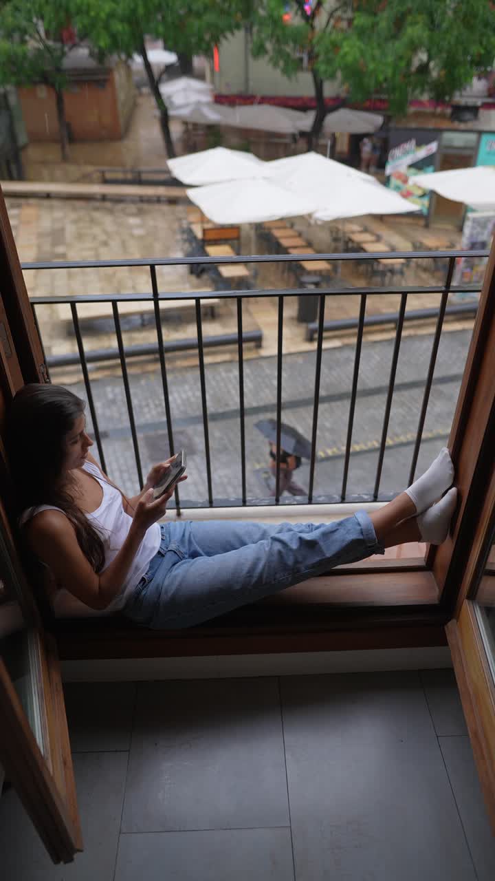 mujer relajándose en un asiento de la ventana en un clima lluvioso