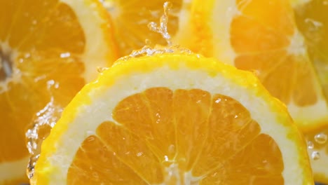 agua disparada en cámara lenta cayendo sobre una rebanada de naranja giratoria, concepto de fruta fresca
