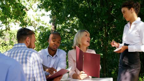 waitress taking order from group of friends sitting in restaurant