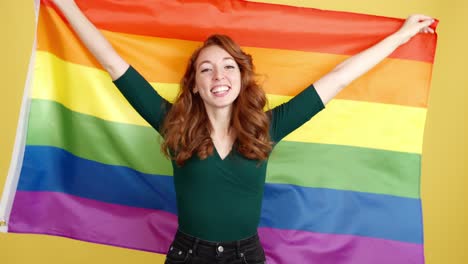 joyful redhead woman waving rainbow flag
