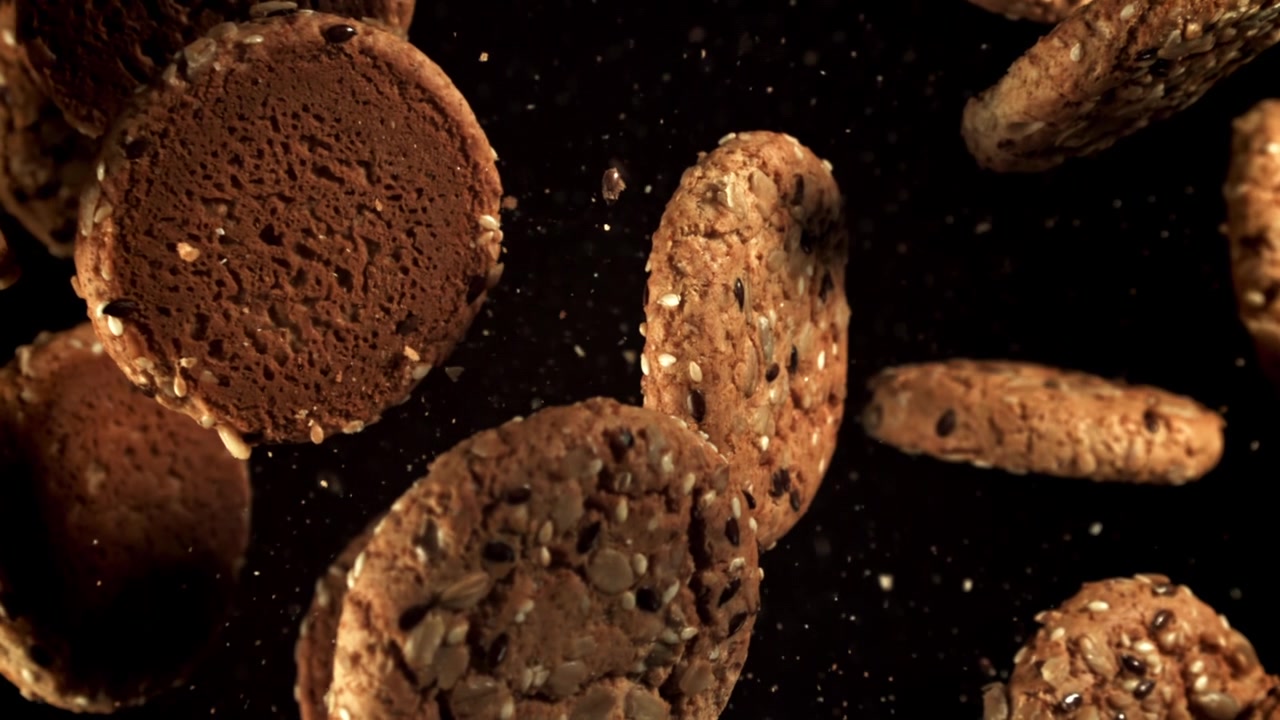Multigrain Cookies with Seeds Falling in Slow Motion on Black Background