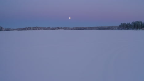 Vista-Aérea-Luna-Brillando-Sobre-Vasto-Congelado-Etéreo-Escandinavo-Paisaje-Cubierto-De-Nieve