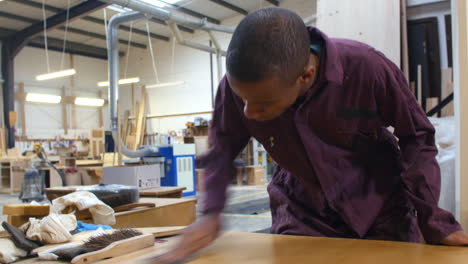 male apprentice finishing wood in carpentry workshop