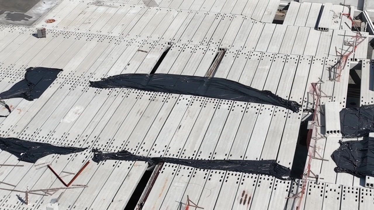 Moderne præfabrikeret betonbygning under opførelse med præfabrikerede søjler, vægpaneler og huldæk, luftfoto