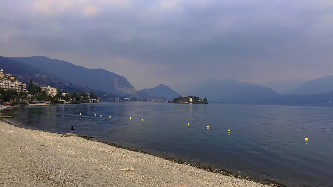 Lakeshore of Lake Maggiore with hotels and Alps mountain range in background on cloudy day, Stresa in Italy