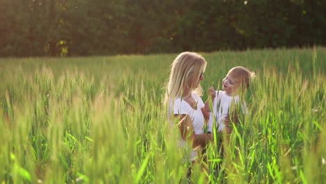 happy family having fun. baby boy with brown curly hair and his mother with ginger hair showing thumb up each other. outdoor shot