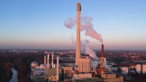 Slow-dolly-toward-powerplant-letting-off-steam-at-sunset-in-Brunswick,-Germany