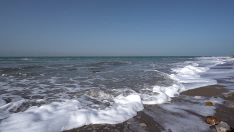 a blue and clear sky above the crashing waves of dead sea in slow motion in 100 frames per second