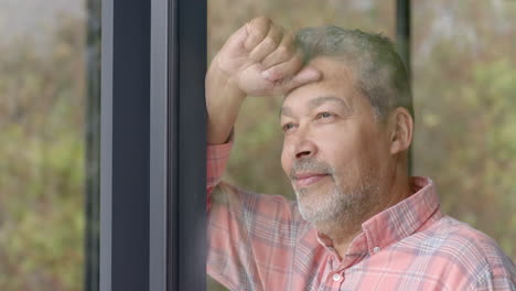 happy senior biracial man looking out of window at countryside, copy space, slow motion