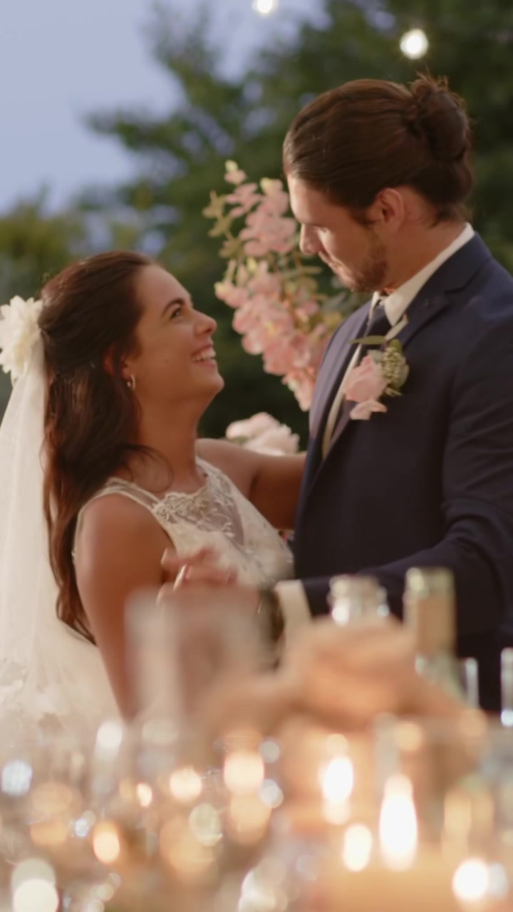 Video vertical: Pareja romántica en la recepción, invitados aplaudiendo, el novio guiando a la novia, velas encendidas
