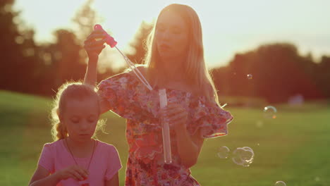 Glückliche-Familie,-Die-Den-Sonnenuntergang-Im-Garten-Genießt.-Frau-Mit-Tochter-Bläst-Seifenblasen