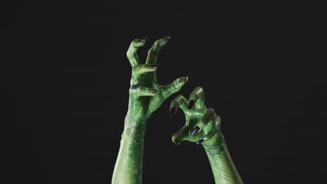 Video-of-halloween-green-monster-hands-with-copy-space-on-black-background