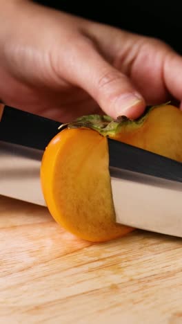 manos cortando caqui con un cuchillo afilado