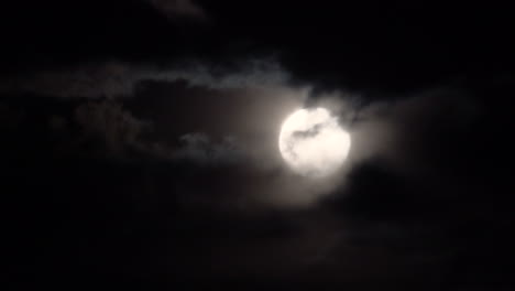 full moon with spooky clouds passing in front on a dark night