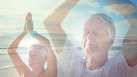 animation of glowing light over senior couple practicing yoga by seaside