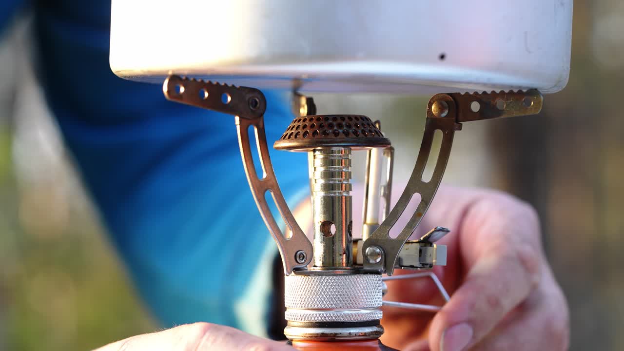 hombre quemando estufa de campamento a agua hirviendo