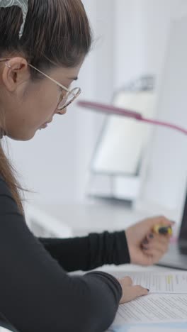 focused woman highlighting documents while studying or working