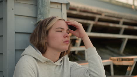 close-up of young lady resting head on hand, her expression reflecting deep contemplation, warm sunlight in background creates gentle glow