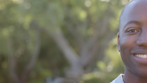 smiling african american man outdoors in nature, enjoying sunny day in park, copy space