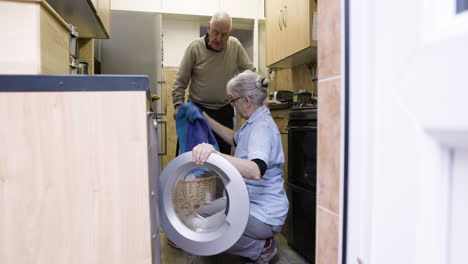 senior man and caregiver using washing machine