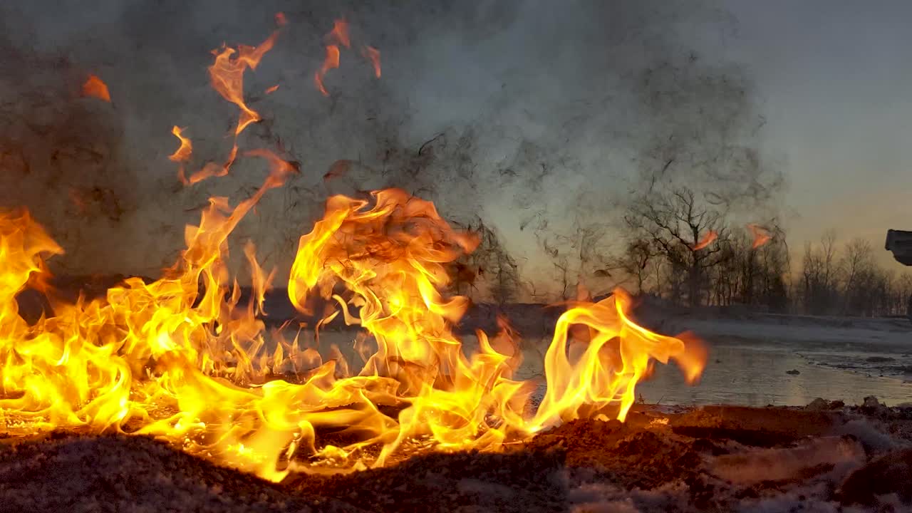 el derrame de petróleo en llamas envía humo negro sucio al cielo mientras el sol sale en el fondo