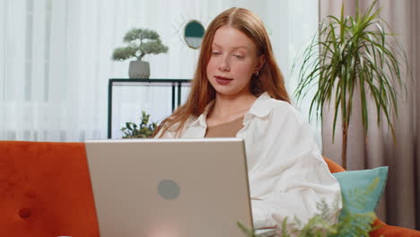 Teenager red hair girl sitting on home couch making video conference call with friends or family