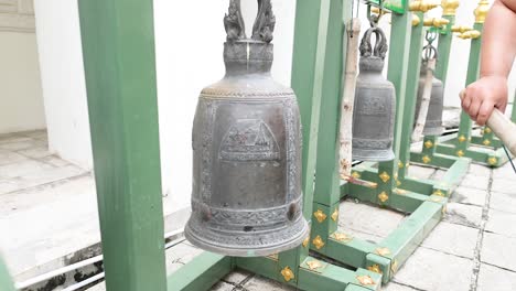 person striking bell at prayurawongsawat temple