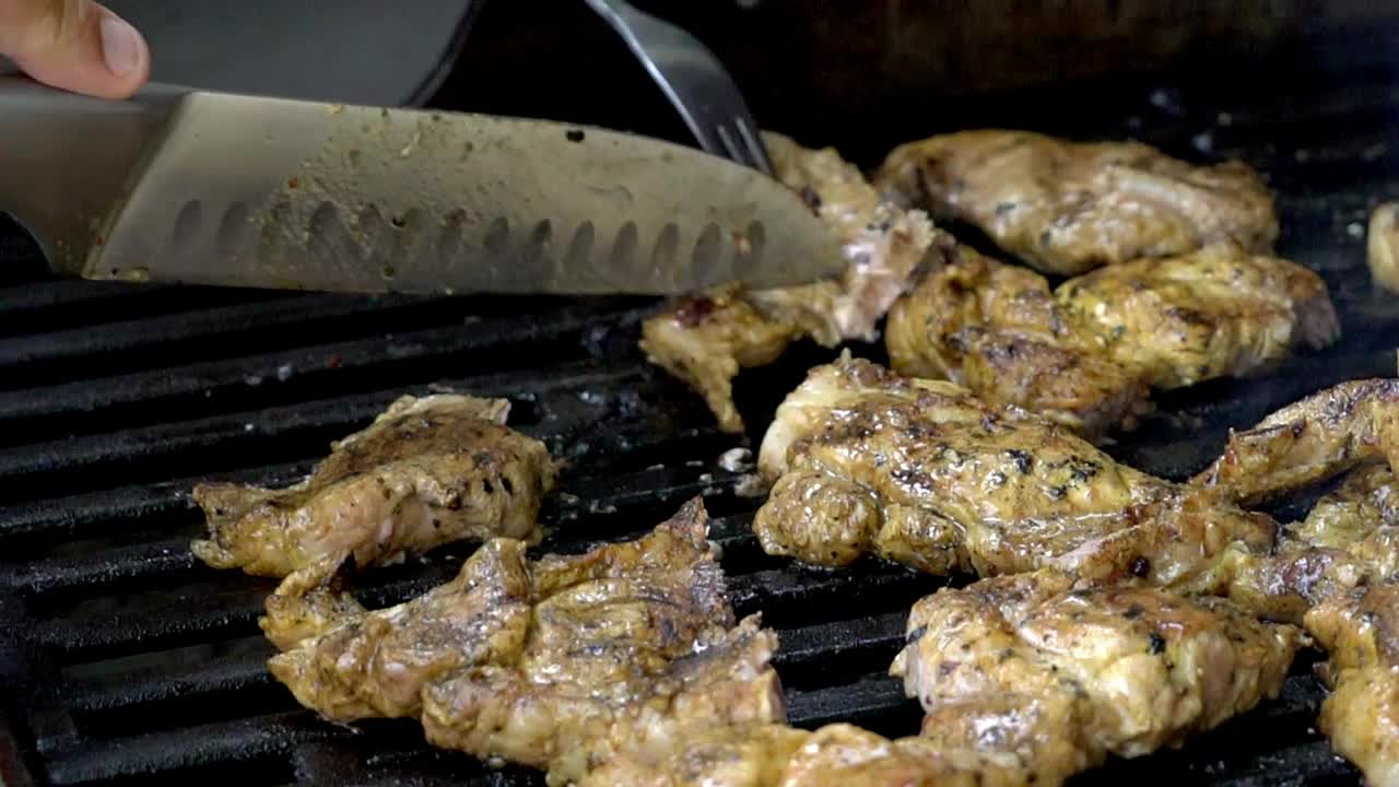 Cooking chicken on a bbq, cutting chicken pieces into smaller portions