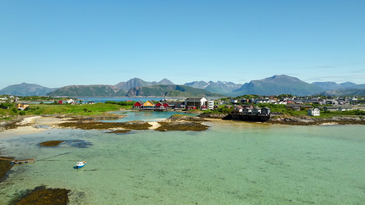 Summer island hotel and colorful seaside houses in Troms, Norway. Aerial View, scenic coastal resort area with clear waters, beaches, and mountains in the background