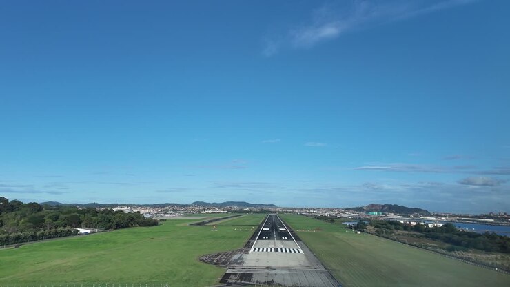 Het meeslepende perspectief van een piloot vanuit de cockpit van een jet tijdens de laatste nadering voor de landing op de landingsbaan van de luchthaven van Santander aan de kust, op een rustige, zonnige ochtend onder een blauwe hemel