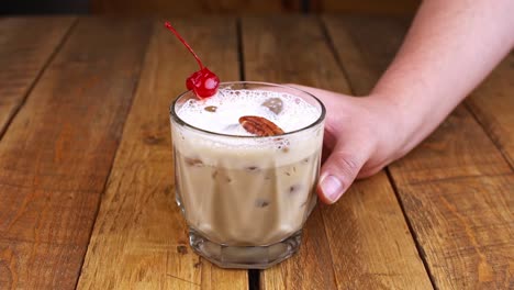 Nahaufnahme-Einer-Hand,-Die-Einen-Cocktail-Auf-Kahlua-Basis-Mit-Kaffee,-Alkohol-Und-Milch-Auf-Einem-Holztisch-Dreht