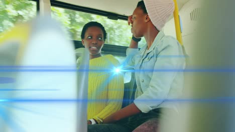 Animation-of-blue-light-beams-over-two-african-american-woman-on-bus-talking