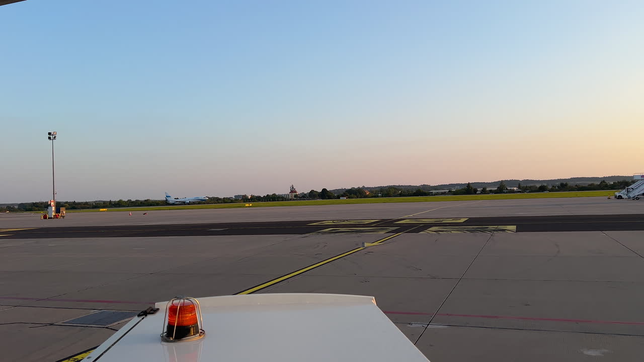 Eine Flughafenlandebahn, getaucht in das sanfte Licht der Dämmerung, mit der Silhouette von Flugzeugen vor dem verblassenden Licht