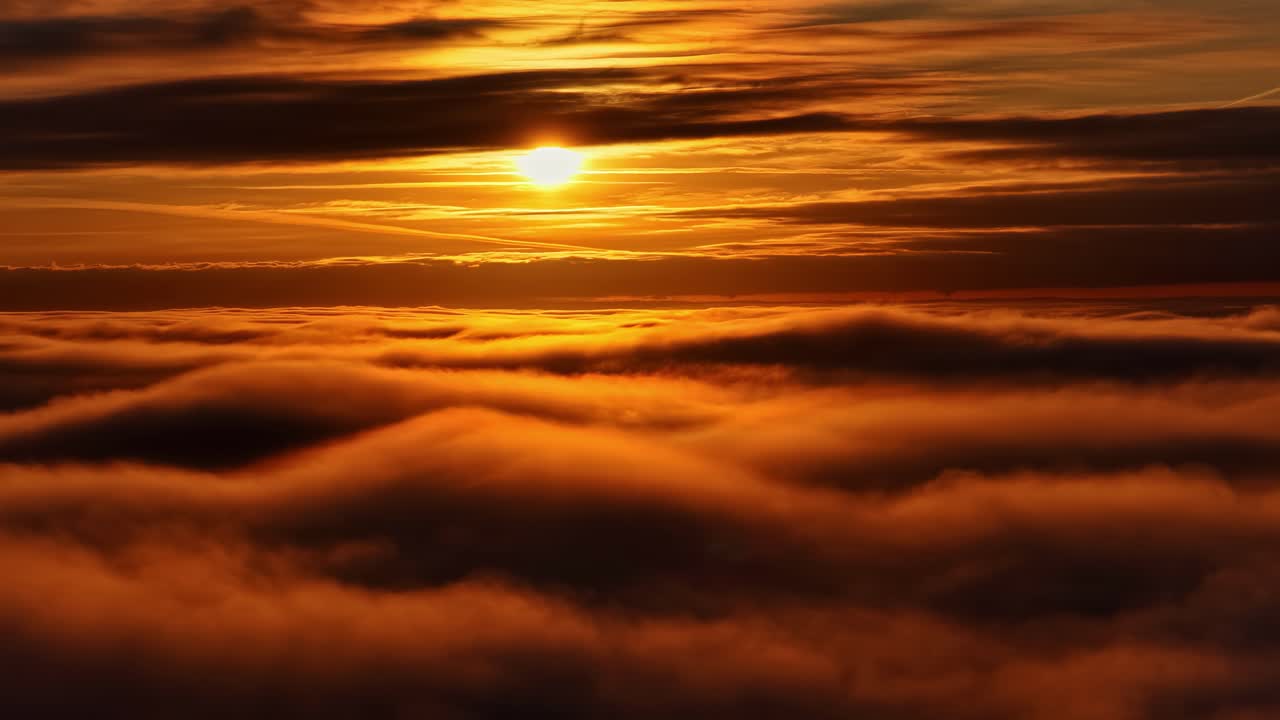Goldenes Sonnenuntergangslicht erstreckt sich über glatte Wolkenschichten und erzeugt einen warmen, leuchtenden Horizont mit weichen Texturen und satten Abendfarben