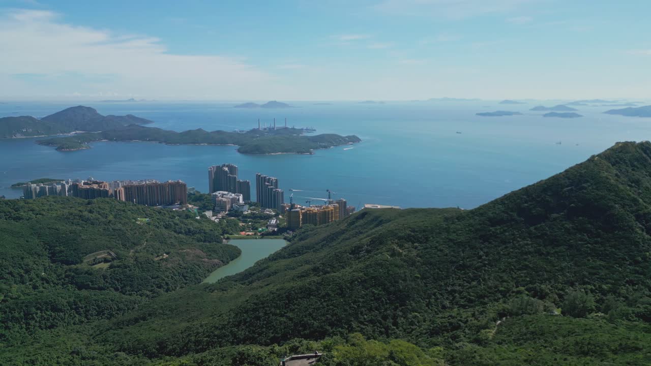 Aerial drone footage capturing Hong Kong’s lush mountains overlooking the ocean, showcasing scenic coastal landscapes, natural greenery, and panoramic vistas ideal for travel