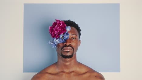studio portrait of shirtless man wearing flower eyepatch