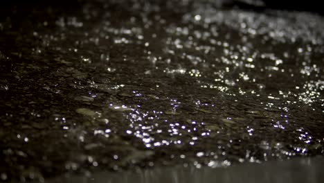 rain falling on pavement asphalt surface at night, background loop