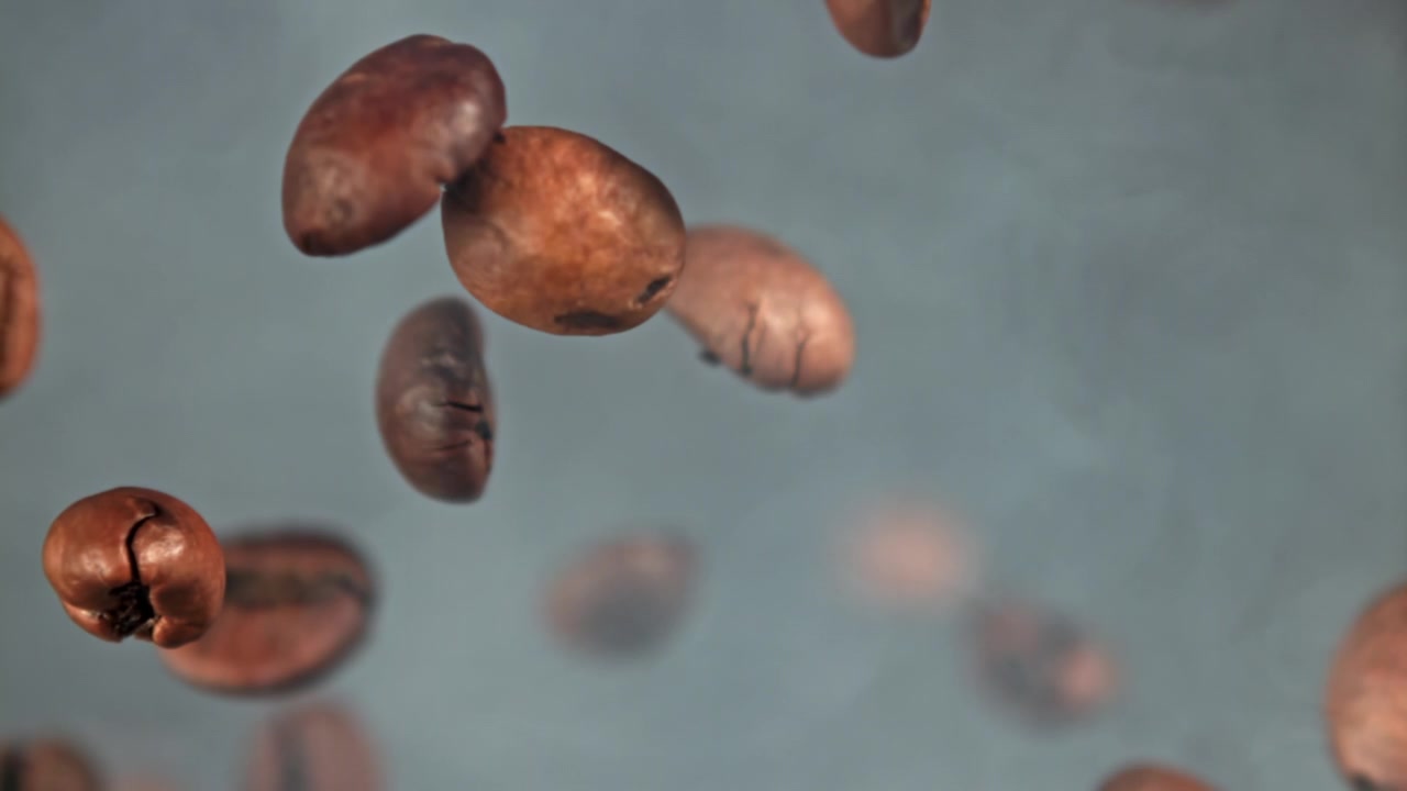 Chicchi di caffè tostati che cadono al rallentatore con fumo