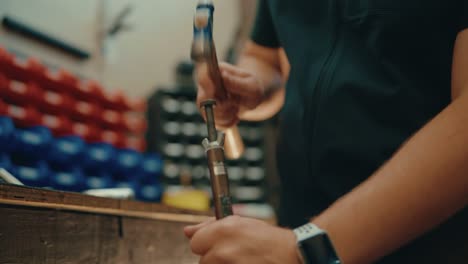 manos masculinas martillando en cámara lenta en el taller para la instalación de clubes de golf personalizados