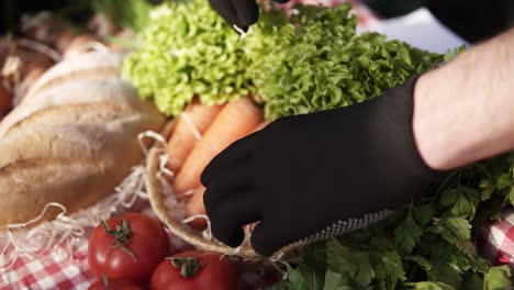 Close-Up-Of-Male-Farmer-Hands-In-Black-Gloves-Arranging-Organic-Food-Salad,-Perfect-Shape-Organic-Carrots-In-Farm-Market-Standing-Indoors-In-Greenhouse