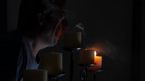 hombre soplando todas las velas de un candelabro