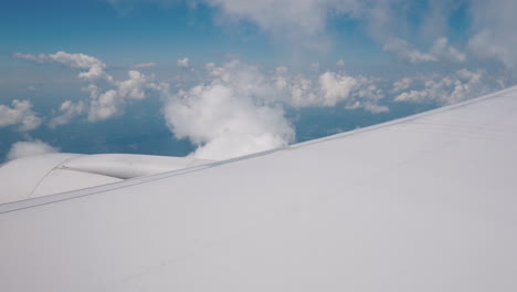 un ala con un motor de avión en vuelo contra el telón de fondo de las nubes y el cielo azul