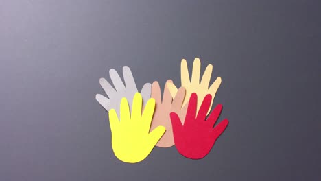 Close up of hands together made of colourful paper on gray background with copy space