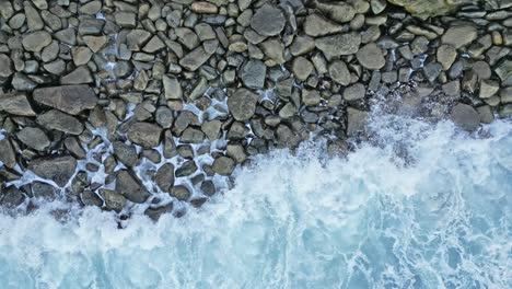 Drone-shot-of-frantic-Sea-lion-getting-to-shore-and-climbing-up-rocks-with-waves-crashing-in-La-Jolla,-California-during-king-tide